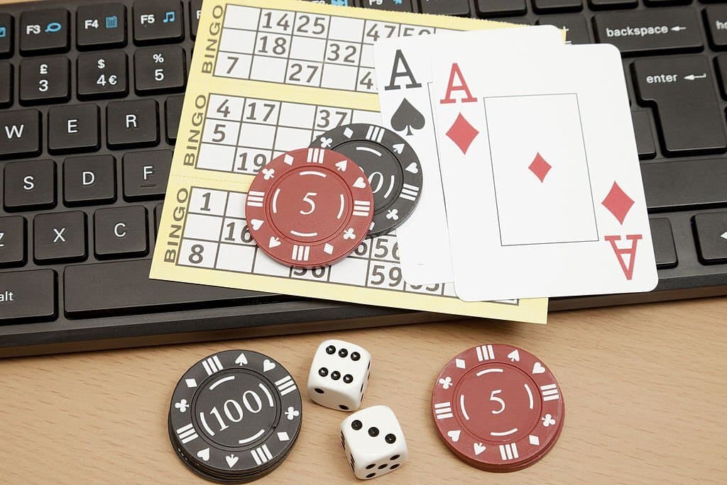 "A computer keyboard with bingo cards, playing cards, poker chips and dice."